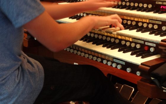 A person seated at an organ playing the keys.